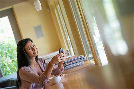 simsearch:6118-07203820,k - A woman having a cup of coffee and using a smart phone. Stock Photo - Premium Royalty-Free, Code: 6118-07203782