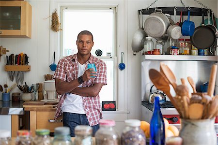 simsearch:6118-07203820,k - A man holding a drink standing in a farmhouse kitchen. Stock Photo - Premium Royalty-Free, Code: 6118-07203795