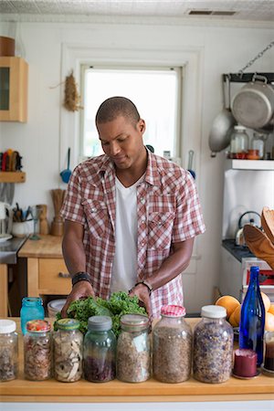 simsearch:6118-07203820,k - A young man in a kitchen preparing salad leaves and vegetables. Stock Photo - Premium Royalty-Free, Code: 6118-07203796
