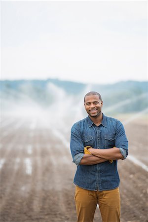 simsearch:6118-07203696,k - An organic vegetable farm, with water sprinklers irrigating the fields. A man in working clothes. Stock Photo - Premium Royalty-Free, Code: 6118-07203712