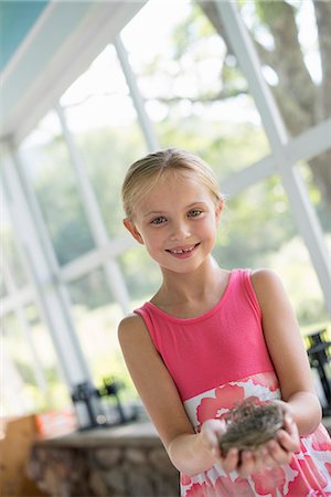 sundress - A young girl in a kitchen wearing a pink dress. Holding a bird's nest. Stock Photo - Premium Royalty-Free, Code: 6118-07203737