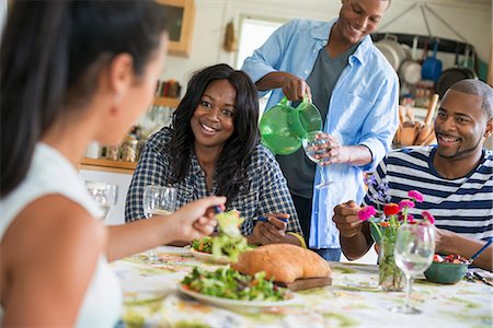 A group of women and men at a meal in a farmhouse kitchen. Stock Photo - Premium Royalty-Free, Code: 6118-07203817