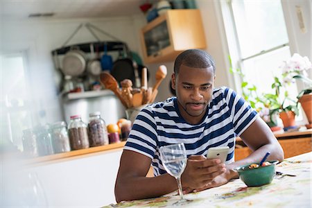 simsearch:6118-07203820,k - A man sitting at a table using a smart phone. Fruit dessert and a glass of wine at hand. Stock Photo - Premium Royalty-Free, Code: 6118-07203820