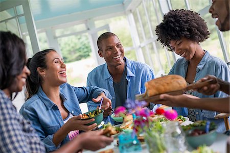 A group of women and men around a table sharing a meal in a farmhouse kitchen. Stock Photo - Premium Royalty-Free, Code: 6118-07203825