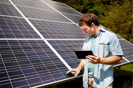 solar panel usa - A farmer closely inspecting the surface of a solar panel on the farm. Stock Photo - Premium Royalty-Free, Code: 6118-07203925