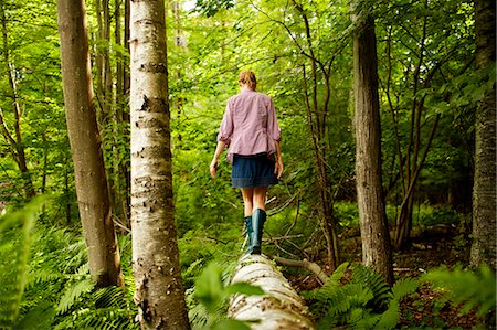 forest building pictures - A woman in wellingtons walking along a fallen tree trunk, in woodland. Stock Photo - Premium Royalty-Free, Code: 6118-07203926