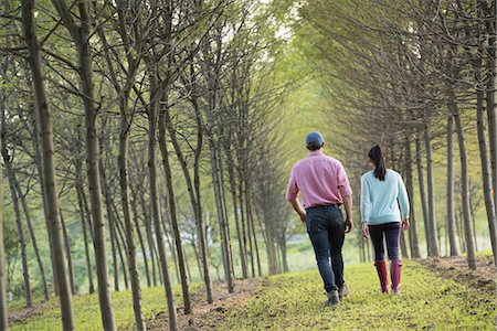 A couple walking between two rows of trees. Stock Photo - Premium Royalty-Free, Code: 6118-07235276
