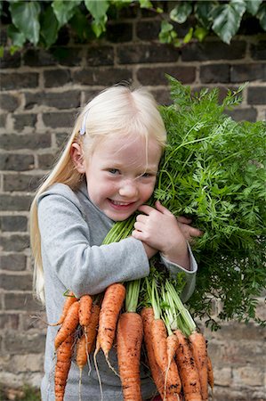 private garden - A young girl holding a large bunch of carrots. Stock Photo - Premium Royalty-Free, Code: 6118-07351141