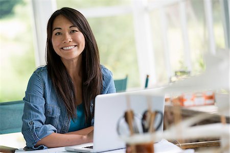 A woman in an office, working at a laptop computer. Stock Photo - Premium Royalty-Free, Code: 6118-07351182