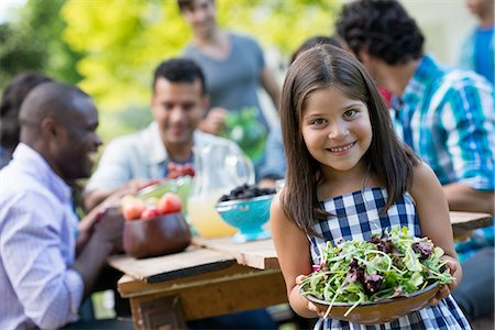 family meals - Adults and children around a table in a garden. A child holding a bowl of salad. Stock Photo - Premium Royalty-Free, Code: 6118-07351194