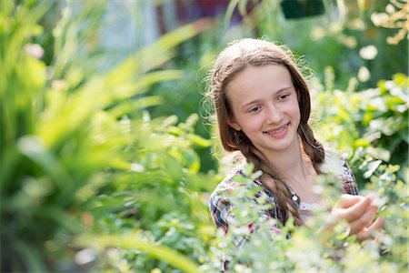 simsearch:6118-07351124,k - Summer on an organic farm. A young girl in a plant nursery full of flowers. Stock Photo - Premium Royalty-Free, Code: 6118-07351129