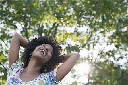 plant (botanical) - A young woman in a flowered summer dress with her hands behind her head, smiling and looking up. Stock Photo - Premium Royalty-Free, Code: 6118-07351594