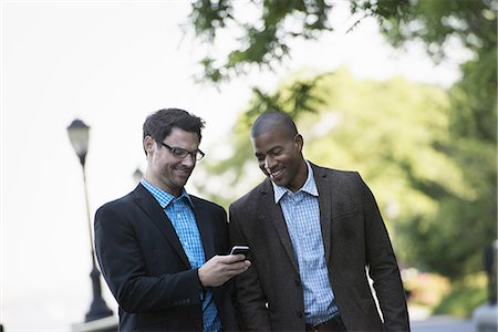 simsearch:6118-07121993,k - Business people in the city. Keeping in touch on the move. Two men walking side by side, one showing the other his smart phone. Stock Photo - Premium Royalty-Free, Code: 6118-07351506