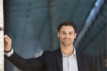 Business people in the city. Keeping in touch on the move. A man in a black jacket and open collared shirt. Stock Photo - Premium Royalty-Free, Code: 6118-07351514