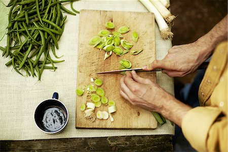 simsearch:6118-07808971,k - A person preparing vegetables, slicing spring onions on a chopping board. Stock Photo - Premium Royalty-Free, Code: 6118-07351674