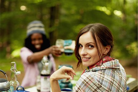 summer meal - Two young woman drinking a toast at a picnic site or campsite in the woods. Stock Photo - Premium Royalty-Free, Code: 6118-07351675