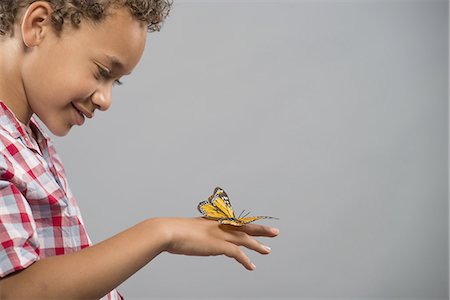 A child with a butterfly on his hand, keeping very still. Stock Photo - Premium Royalty-Free, Code: 6118-07351830