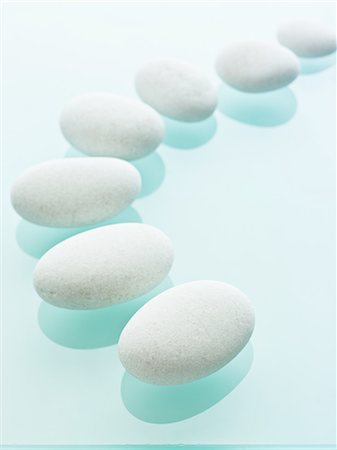 simsearch:6118-07354031,k - Smooth white pebbles of uniform size and colour displayed on a blue reflective glass background. Stock Photo - Premium Royalty-Free, Code: 6118-07351990