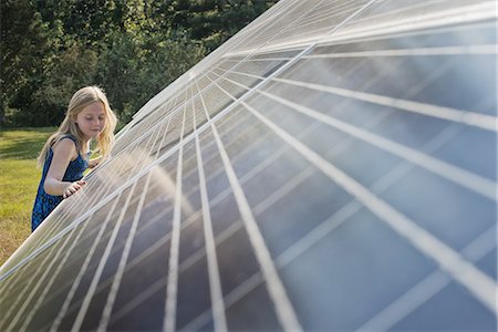 solar panel usa - A young girl standing beside and leaning against a large solar panel installation. Stock Photo - Premium Royalty-Free, Code: 6118-07352084