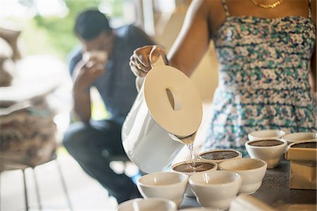 A man sampling in a coffee processing shed, where staff make coffee in small pots and sample the taste to test the blend. Stock Photo - Premium Royalty-Free, Code: 6118-07352131