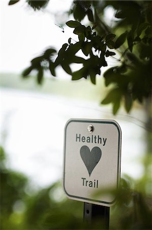 A health trail information sign, a metal marker path sigh with an image of a green heart. Stock Photo - Premium Royalty-Free, Code: 6118-07352376