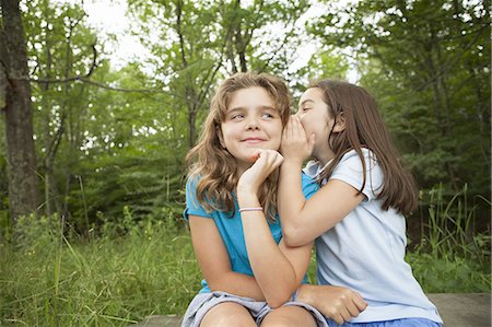 simsearch:649-07596731,k - Two girls, friends sitting side by side, whispering, playing and laughing. Stock Photo - Premium Royalty-Free, Code: 6118-07352389