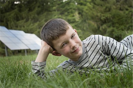 solar panel usa - A boy lying in the grass, beside solar panels. Stock Photo - Premium Royalty-Free, Code: 6118-07352467