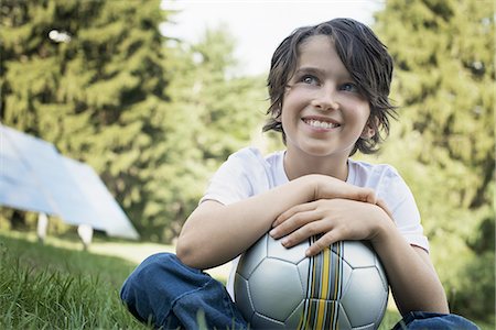 solar panel usa - A boy holding a football, sitting on the grass. Solar panels. Stock Photo - Premium Royalty-Free, Code: 6118-07352464