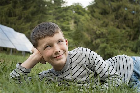 solar panel usa - A boy lying in the grass, beside solar panels. Stock Photo - Premium Royalty-Free, Code: 6118-07352468