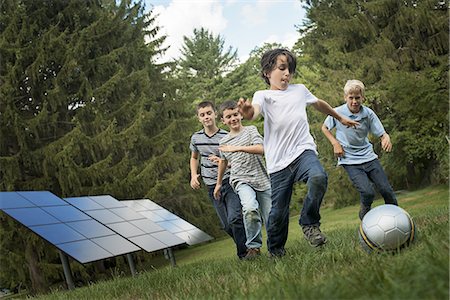 solar panel usa - A group of boys running after a ball past solar panels in the woods. Stock Photo - Premium Royalty-Free, Code: 6118-07352469
