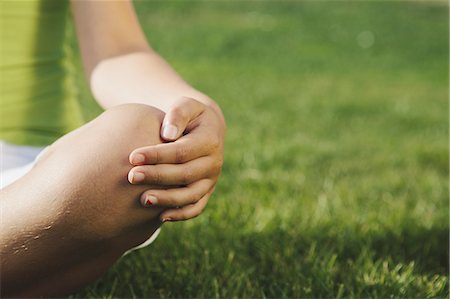 Nine year old girl resting hand on knee, detail, grass in background Stock Photo - Premium Royalty-Free, Code: 6118-07352485