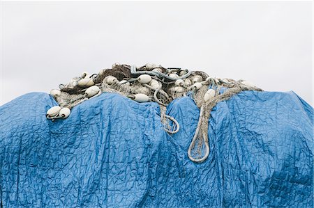 simsearch:6118-08910527,k - A blue tarpaulin covering stacked commercial fishing nets on the dockside at Fisherman's Wharf, Seattle. Photographie de stock - Premium Libres de Droits, Code: 6118-07352675