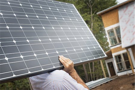 solar panel usa - A workman carrying a large solar panel at a green house construction site. Stock Photo - Premium Royalty-Free, Code: 6118-07352612