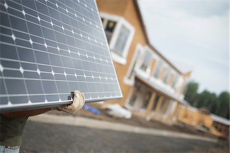 solar panel usa - A workman carrying a large solar panel at a green house construction site. Stock Photo - Premium Royalty-Free, Code: 6118-07352614