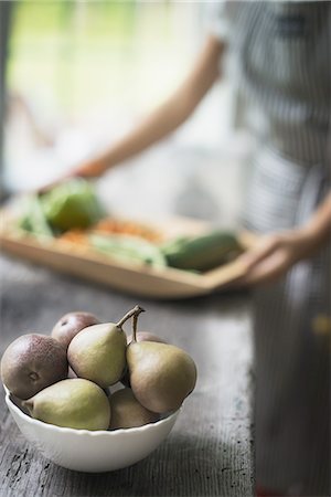 simsearch:6118-07354433,k - A person preparing organic vegetables in a kitchen. Tray of vegetables. Bowl of pears. Stock Photo - Premium Royalty-Free, Code: 6118-07352628