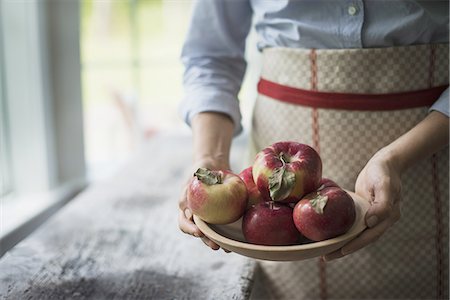 simsearch:6118-07354433,k - A person holding a bowl of organic red skinned apples. Stock Photo - Premium Royalty-Free, Code: 6118-07352632