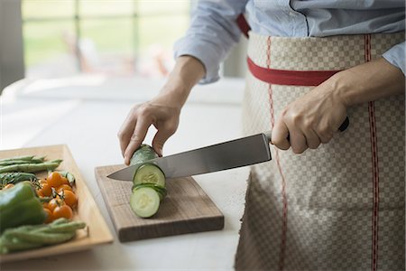 simsearch:6118-07354433,k - A  woman slicing organic vegetables. Cucumbers. Stock Photo - Premium Royalty-Free, Code: 6118-07352637