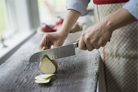 simsearch:6118-07354433,k - A woman slicing a fresh picked fruit, organic pear. Stock Photo - Premium Royalty-Free, Code: 6118-07352635