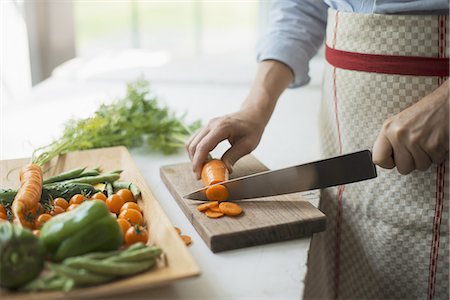 simsearch:6118-07354433,k - A woman preparing fresh vegetables. Slicing a carrot. Stock Photo - Premium Royalty-Free, Code: 6118-07352638