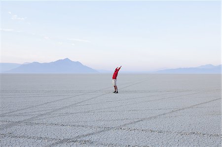 simsearch:6118-07352742,k - A man with arms raised, in the dawn light in Black Rock Desert, Nevada. Stock Photo - Premium Royalty-Free, Code: 6118-07352751