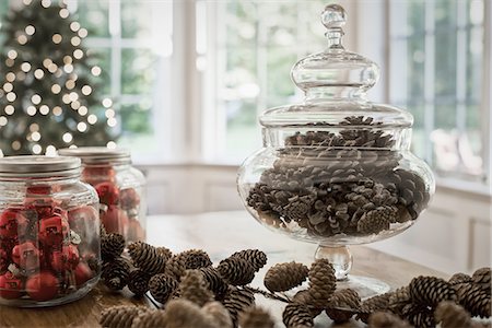 A decorative glass jar of pine cones and red glass baubles on a table top. Christmas decorations. Stock Photo - Premium Royalty-Free, Code: 6118-07352959
