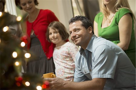 A Christmas gathering, adults and children in a room around a Christmas tree, celebrating together. Photographie de stock - Premium Libres de Droits, Code: 6118-07352992
