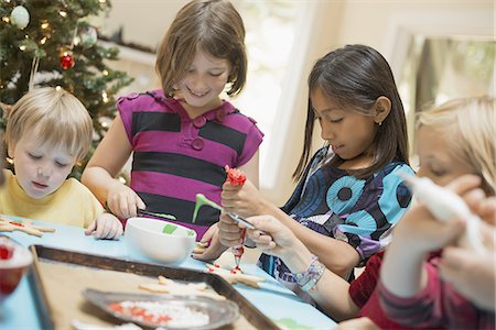 A group of children, girls and boys, around a table, decorating organic Christmas cookies. Stock Photo - Premium Royalty-Free, Code: 6118-07352999