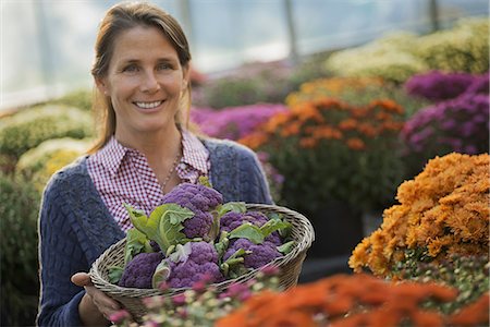 simsearch:6118-07351124,k - A woman holding a bowl of fresh produce, purple sprouting broccoli. Flowering plants. Crysanthemums. Stock Photo - Premium Royalty-Free, Code: 6118-07353351
