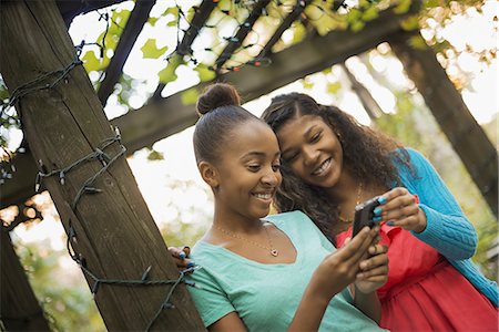 pictures of braids for a 12 year old girl - Scenes from urban life in New York City. Two girls looking at a cell phone or computer pad, laughing. Stock Photo - Premium Royalty-Free, Code: 6118-07353380