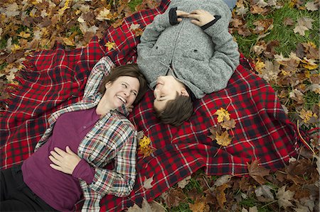 simsearch:6118-07353446,k - Two people, a woman and a child, lying on a red tartan picnic blanket, looking upwards. Stock Photo - Premium Royalty-Free, Code: 6118-07353442