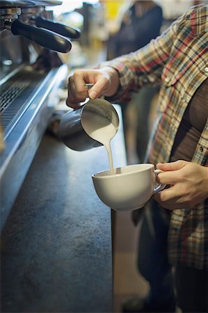 A person, barista, making coffee, and pouring frothed milk from a jug into a cup for a cappuccino. Coffee shop. Photographie de stock - Premium Libres de Droits, Code: 6118-07353467