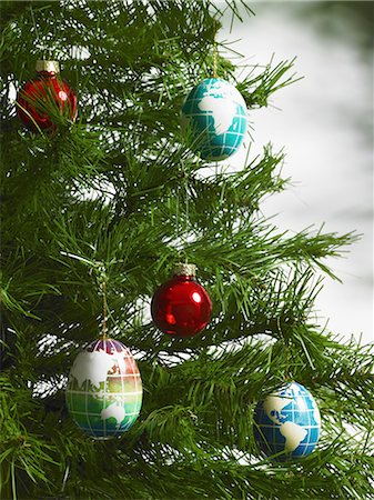 simsearch:6118-07352322,k - Still life. Green leaf foliage and decorations. A pine tree branch with green needles. Christmas decorations. A small group of red and blue tree ornaments. Oblong shapes with continents outlined on a blue background. Stock Photo - Premium Royalty-Free, Code: 6118-07353489