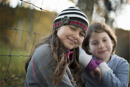 simsearch:6118-07354445,k - Two young girls side by side outdoors on a farm. Leaning on a fence post. Stock Photo - Premium Royalty-Free, Code: 6118-07353409