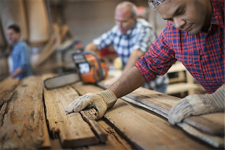 simsearch:6118-07353279,k - A reclaimed lumber workshop. A group of people working. A man measuring and checking planks of wood for re-use and recycling. Foto de stock - Sin royalties Premium, Código: 6118-07353424
